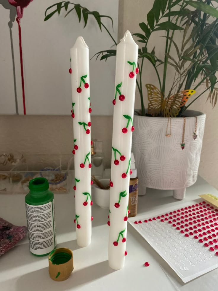 two candles with cherries on them are sitting on a table next to other items