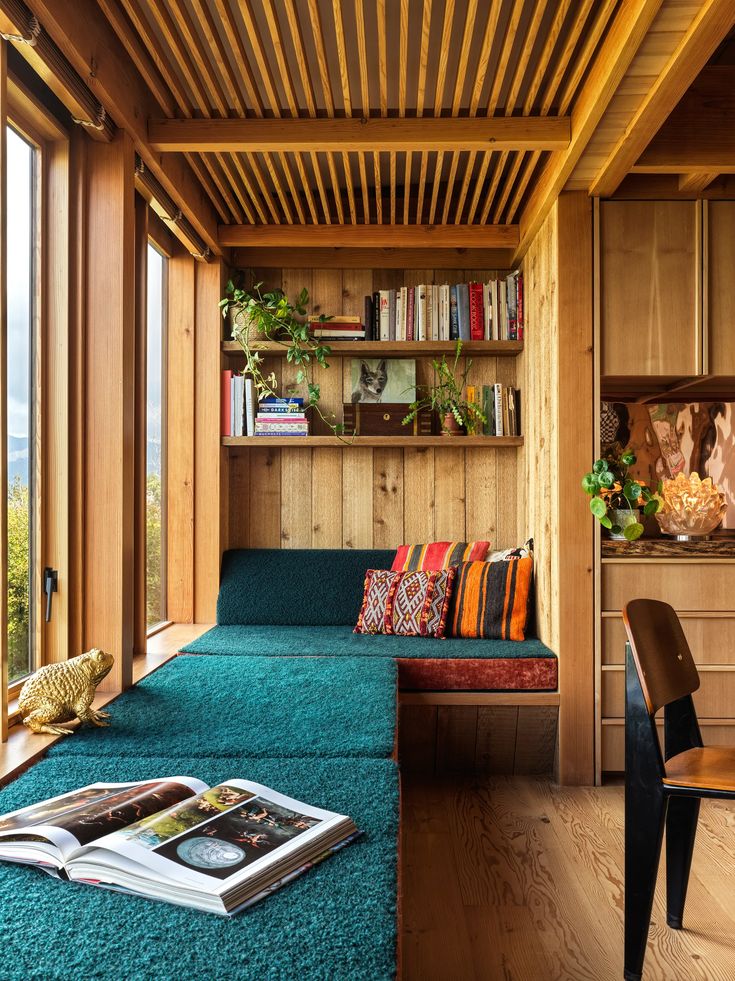 a living room filled with lots of furniture next to a wooden wall covered in books