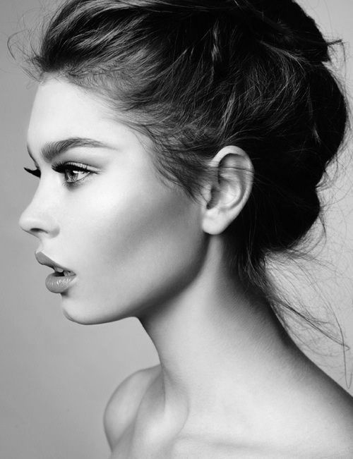 a black and white photo of a woman's face with her hair in a bun