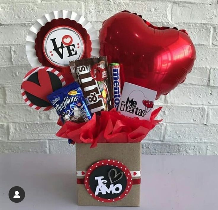 a valentine's day gift box filled with chocolates, candy and balloons in front of a brick wall