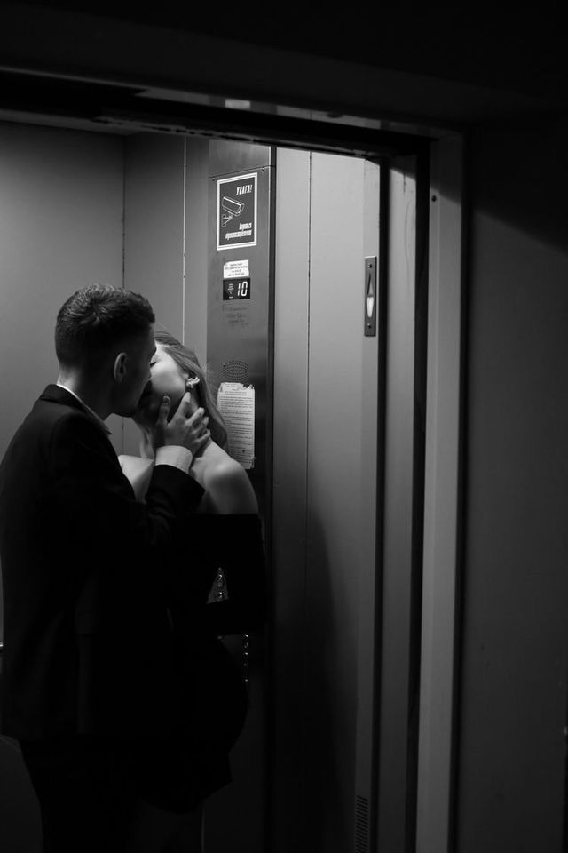 a man in a suit is talking on his cell phone while standing next to an elevator