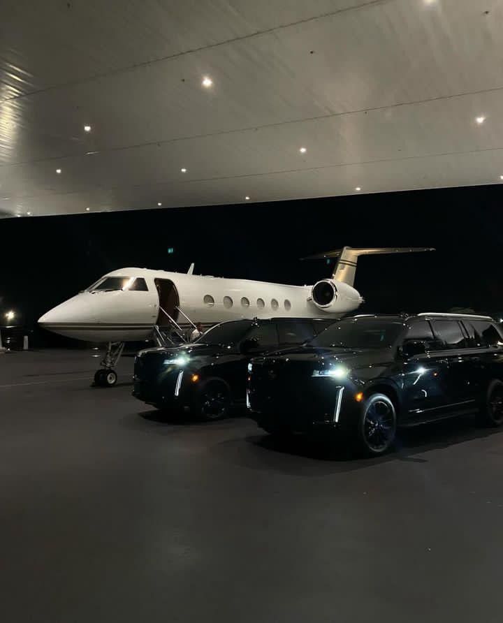 two cars parked in front of an airplane and a private jet on the tarmac