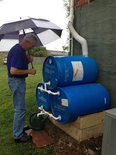 a man holding an umbrella standing next to two kegs