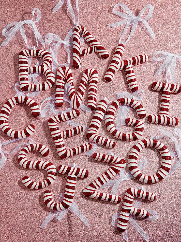 candy canes are arranged in the shape of numbers on a pink surface with white ribbons