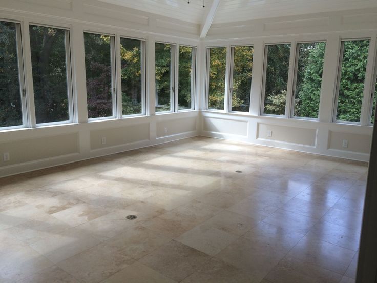 an empty room with large windows and tile flooring on the side of the room