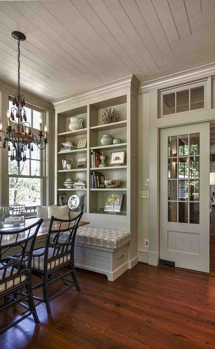 a dining room table and chairs with built in bookshelves next to the door