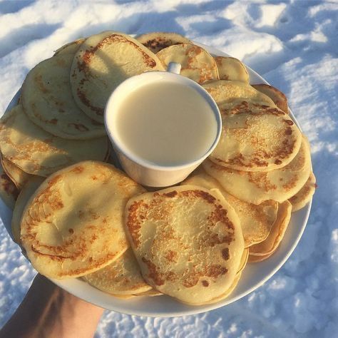 a white plate topped with pancakes covered in powdered sugar next to a person's hand