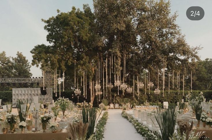 an outdoor wedding venue with white flowers and greenery in the foreground, surrounded by tall trees