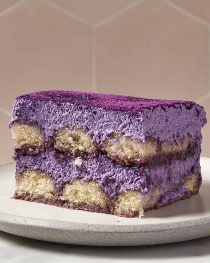 a piece of cake on a plate with purple icing and white chocolate in the middle