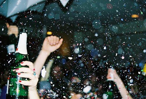 people are holding umbrellas in the rain and one person is holding a beer bottle