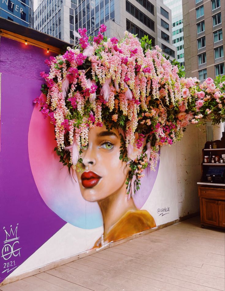 there is a large mural on the side of a building with flowers in it's hair