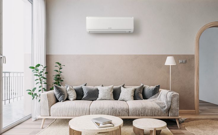 a living room with a couch, coffee table and air conditioner on the wall