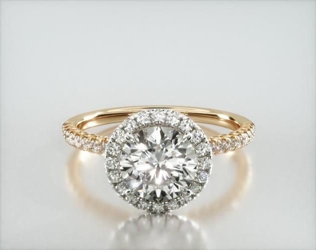 an engagement ring with a halo setting and round diamonds on the band, set in yellow gold