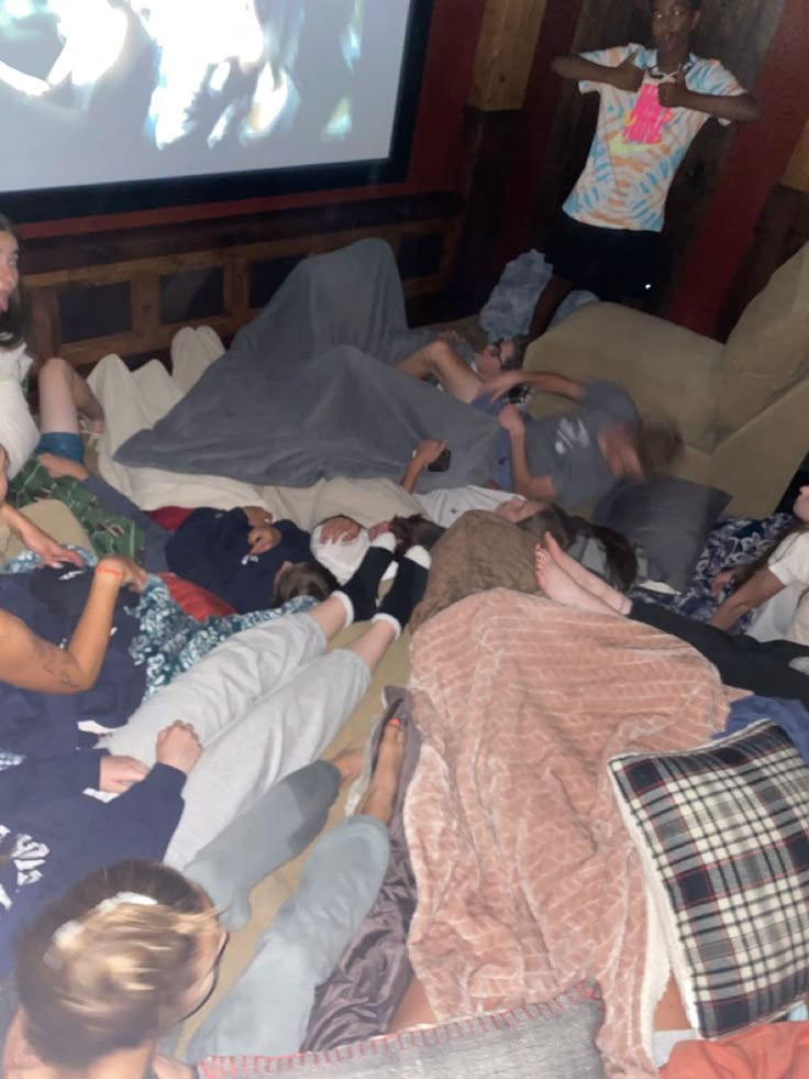 a group of people laying on top of a bed in front of a flat screen tv