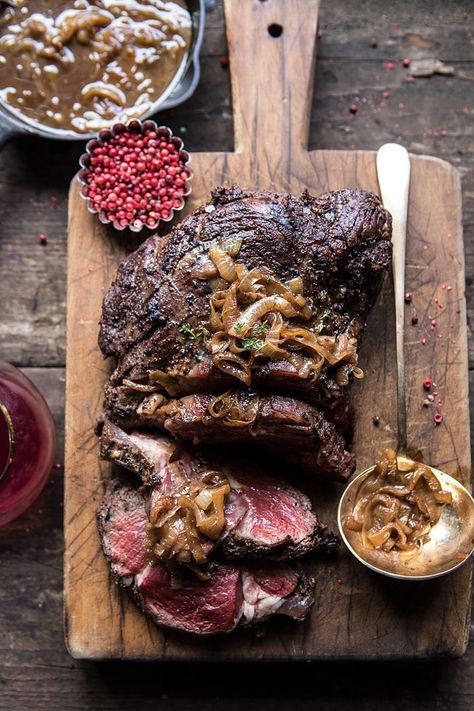 a large piece of steak on a wooden cutting board with a spoon and sauce next to it