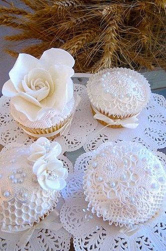 three cupcakes decorated with white lace and flowers