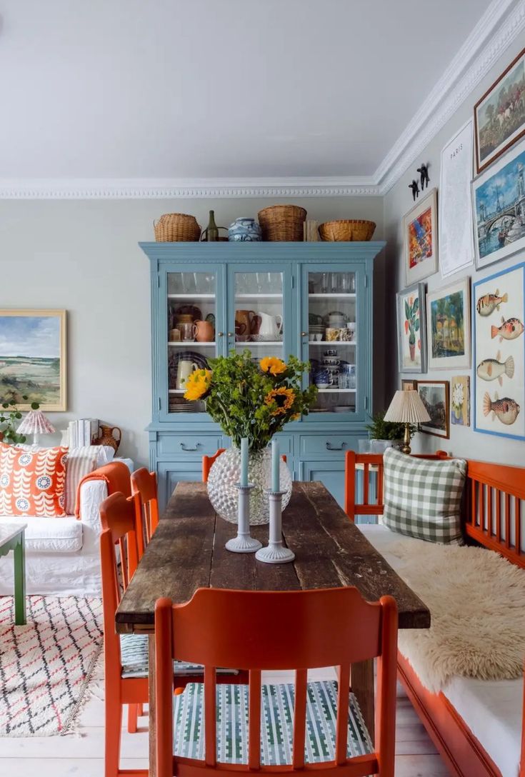 a dining room table with chairs and pictures on the wall above it, along with other furniture