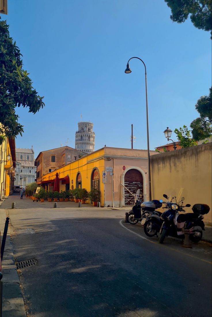 an empty street with scooters parked on the side and buildings in the background