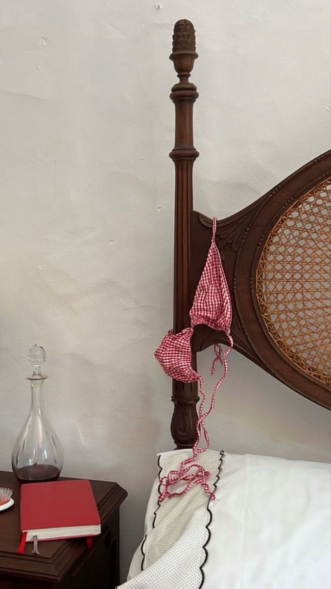 a bed with a wooden headboard and white sheets next to a lamp on a table