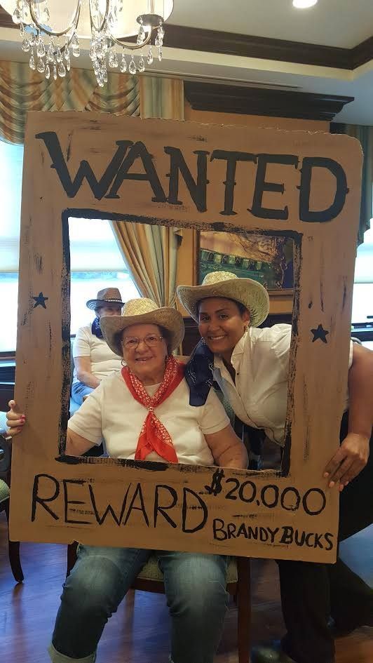 two people sitting in a chair holding up a sign that says wanted reward brandybucks