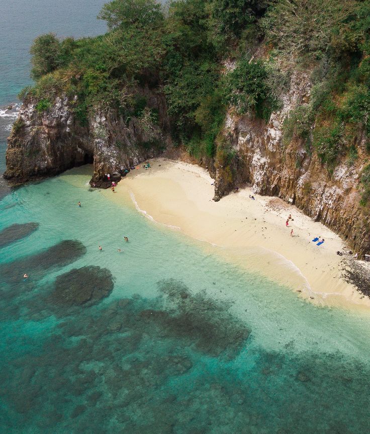 an aerial view of a sandy beach with clear blue water and people on the sand