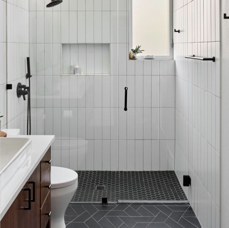 a white tiled bathroom with black accents