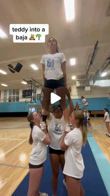 three girls in white shirts and black shorts are standing on top of each other while one girl is holding up another woman's head