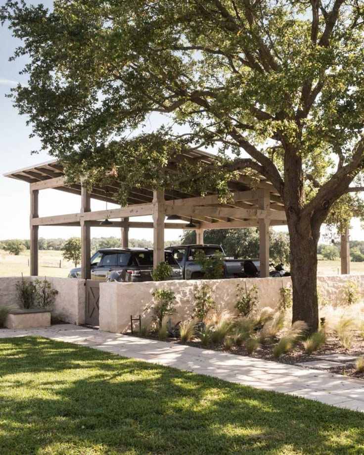 an outdoor covered area with cars parked under a tree