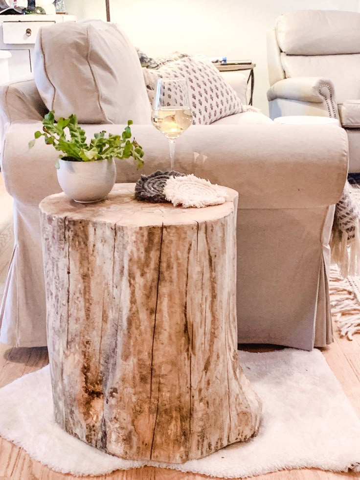 a glass of wine sitting on top of a tree stump in front of a couch