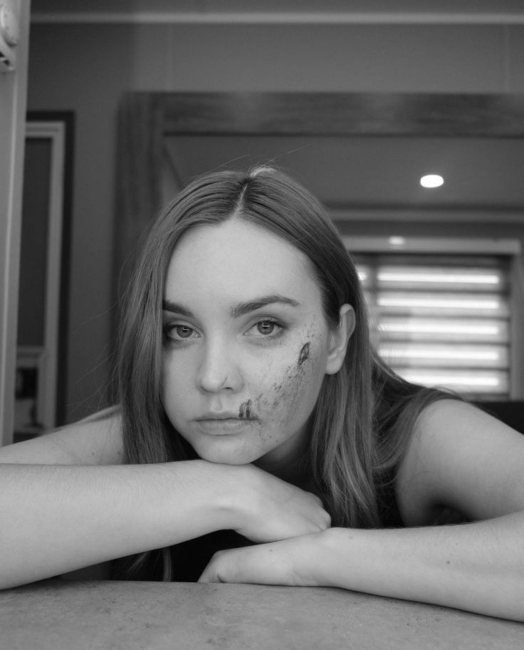 a woman with makeup on her face sitting at a table