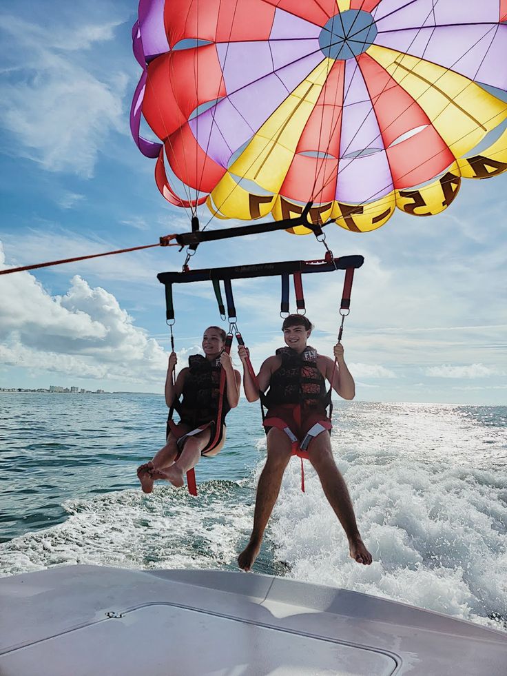 two people on a boat being pulled by a parachute