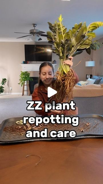 a woman holding up a plant on top of a table