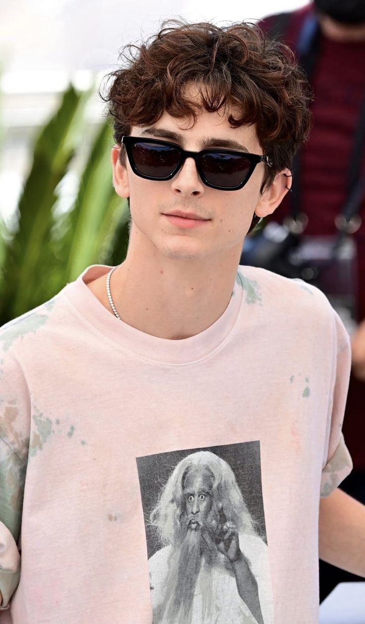 a young man wearing sunglasses and a t - shirt with an image of jesus on it