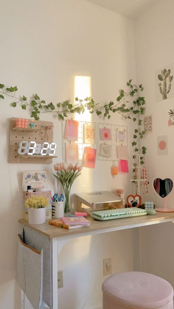 a white desk topped with a laptop computer next to a plant covered wall