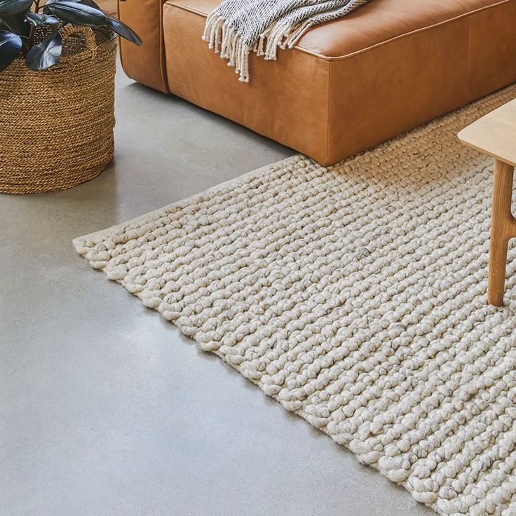 a living room with a brown couch and rugs on the floor next to a coffee table