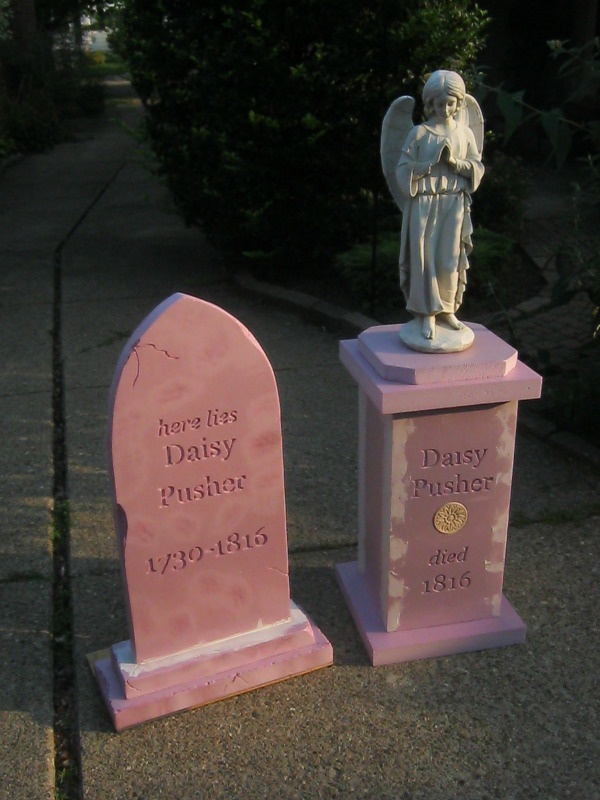 two pink headstones with an angel statue on top and the names of their babies