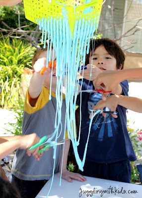 two young boys are playing with toothbrushes in front of a table full of other children