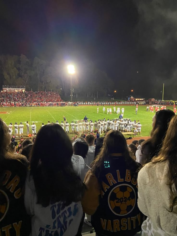 a group of people standing on top of a field next to each other at night