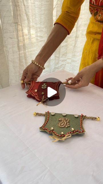 two women are making decorative items on a white table cloth covered table with curtains in the background