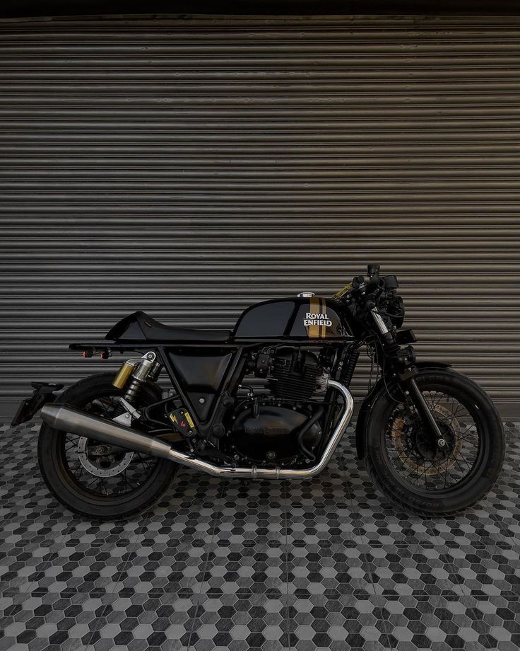 a black motorcycle parked in front of a garage door next to a checkered floor