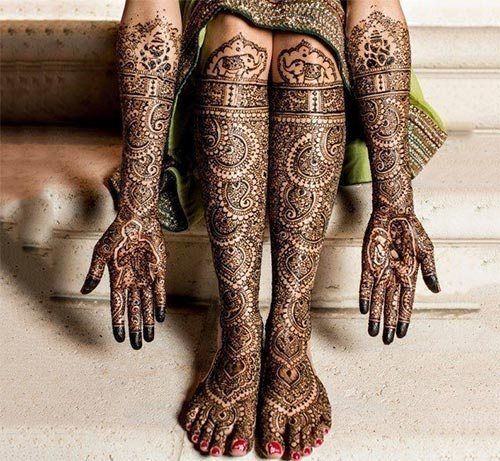 the legs and feet of a woman with henna tattoos on their body, sitting down