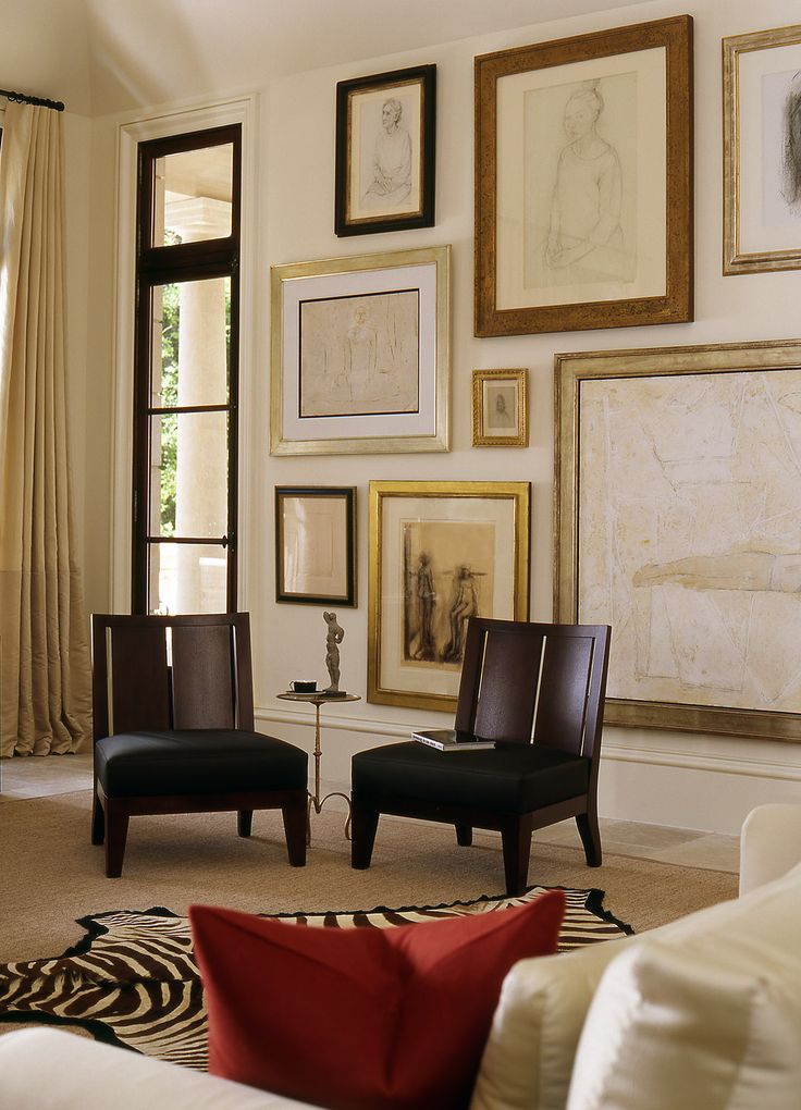 a living room filled with furniture and framed pictures on the wall above it's windows