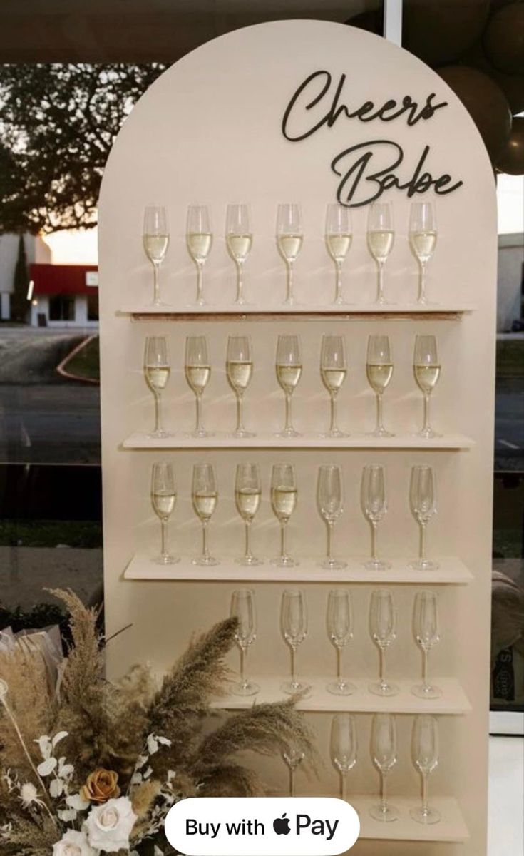 there is a wine glass rack with many glasses on it and flowers in the vase