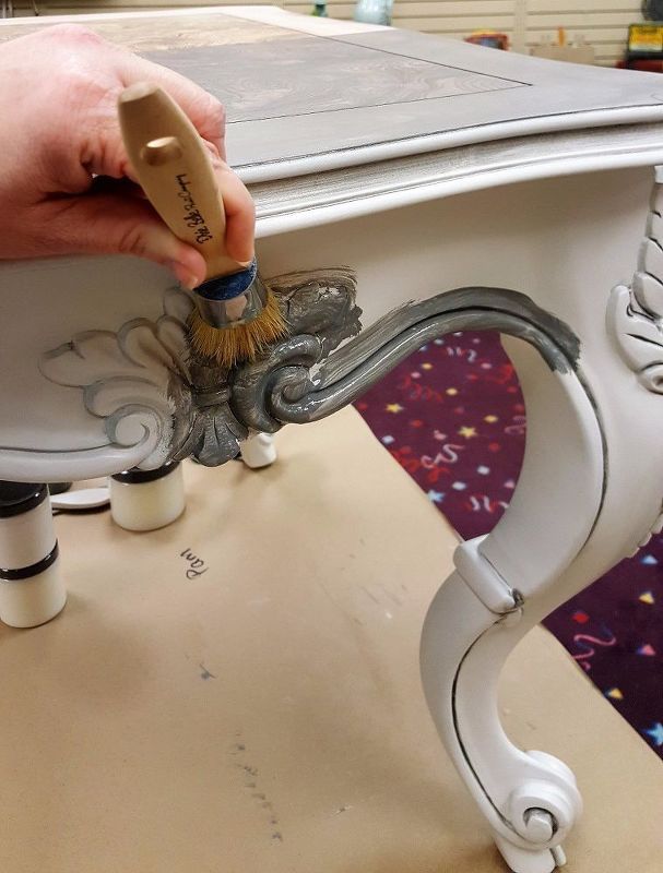 someone using a brush to paint a white table