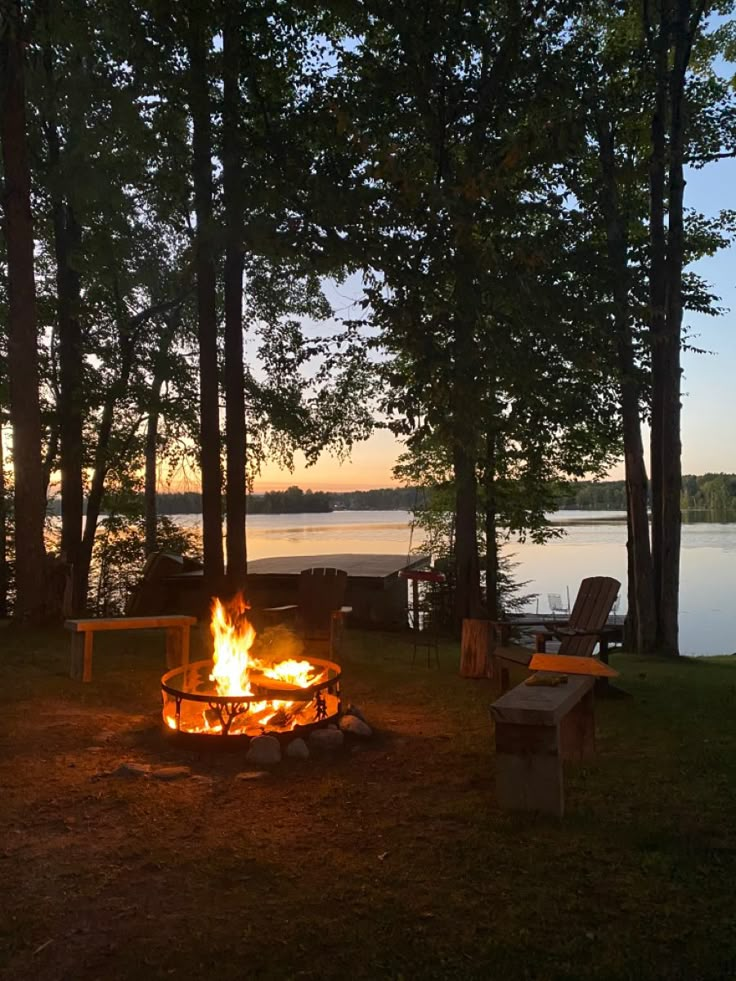 a fire pit sitting in the middle of a forest next to a body of water