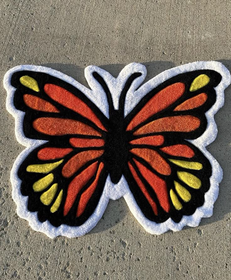 a close up of a butterfly shaped patch on the ground with sand in the background