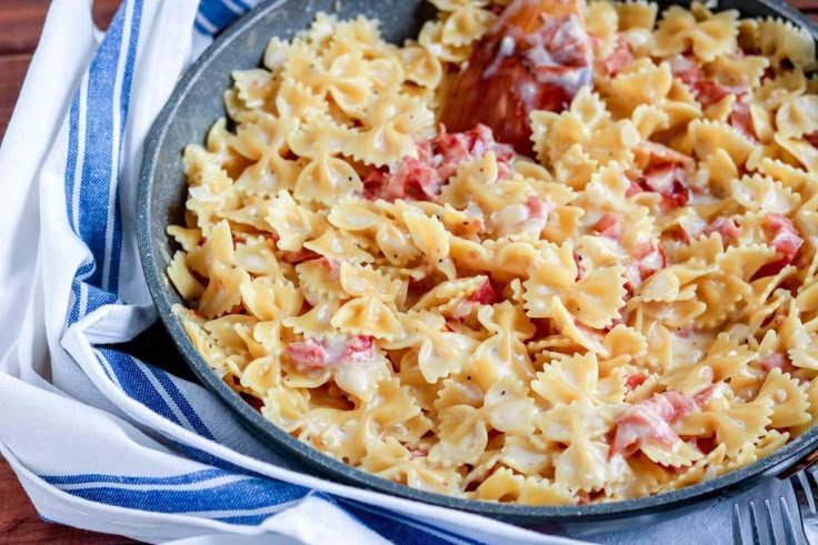 a skillet filled with macaroni and cheese on top of a blue and white towel