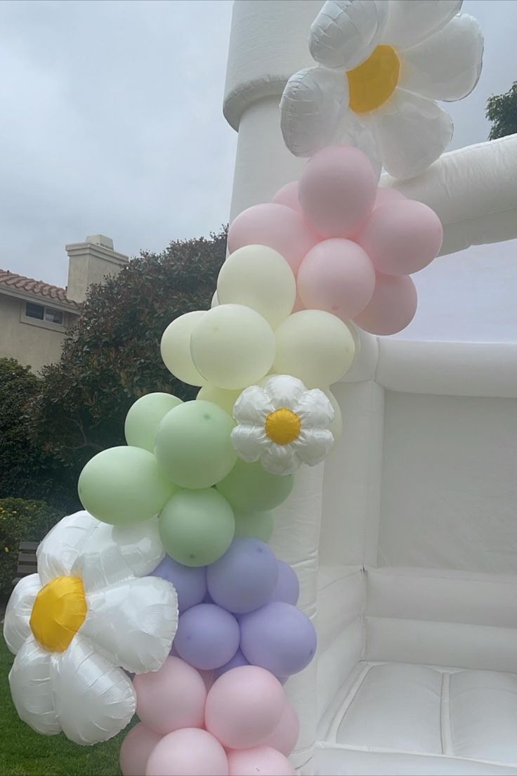 a bunch of balloons that are in the grass with flowers on them and some daisies