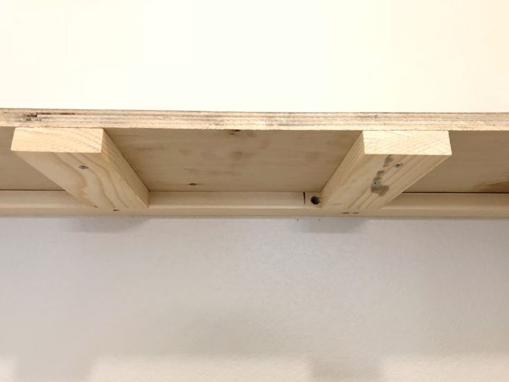 a close up of a wooden shelf against a white wall