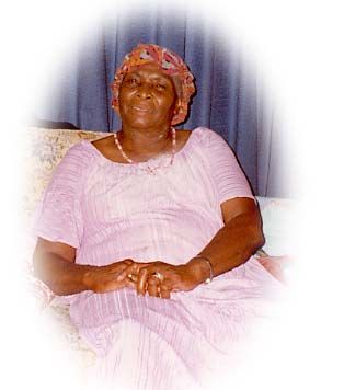 an older woman sitting on top of a couch wearing a pink dress and head scarf